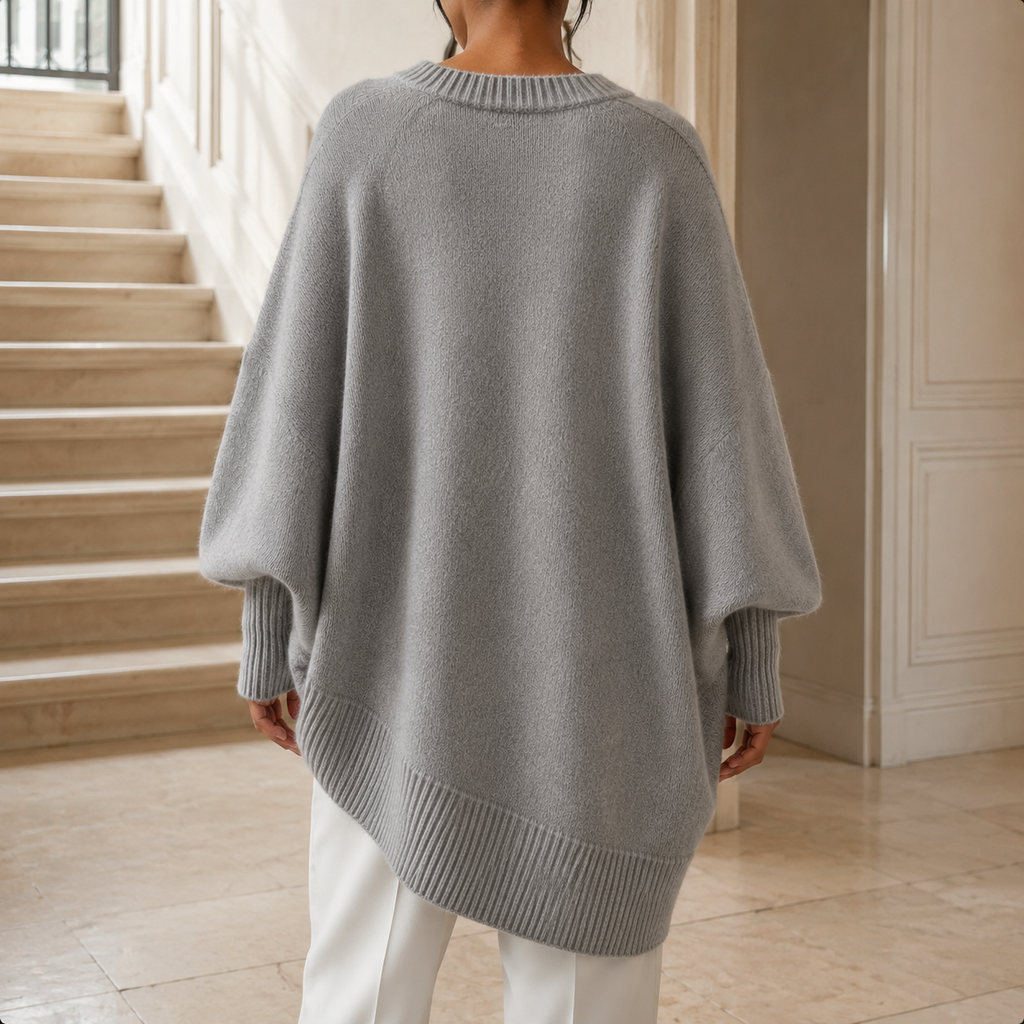 Grey V neck jumper shown from the back with its oversized batwing silhouette and ribbed hem.