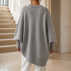 Grey V neck jumper shown from the back with its oversized batwing silhouette and ribbed hem.